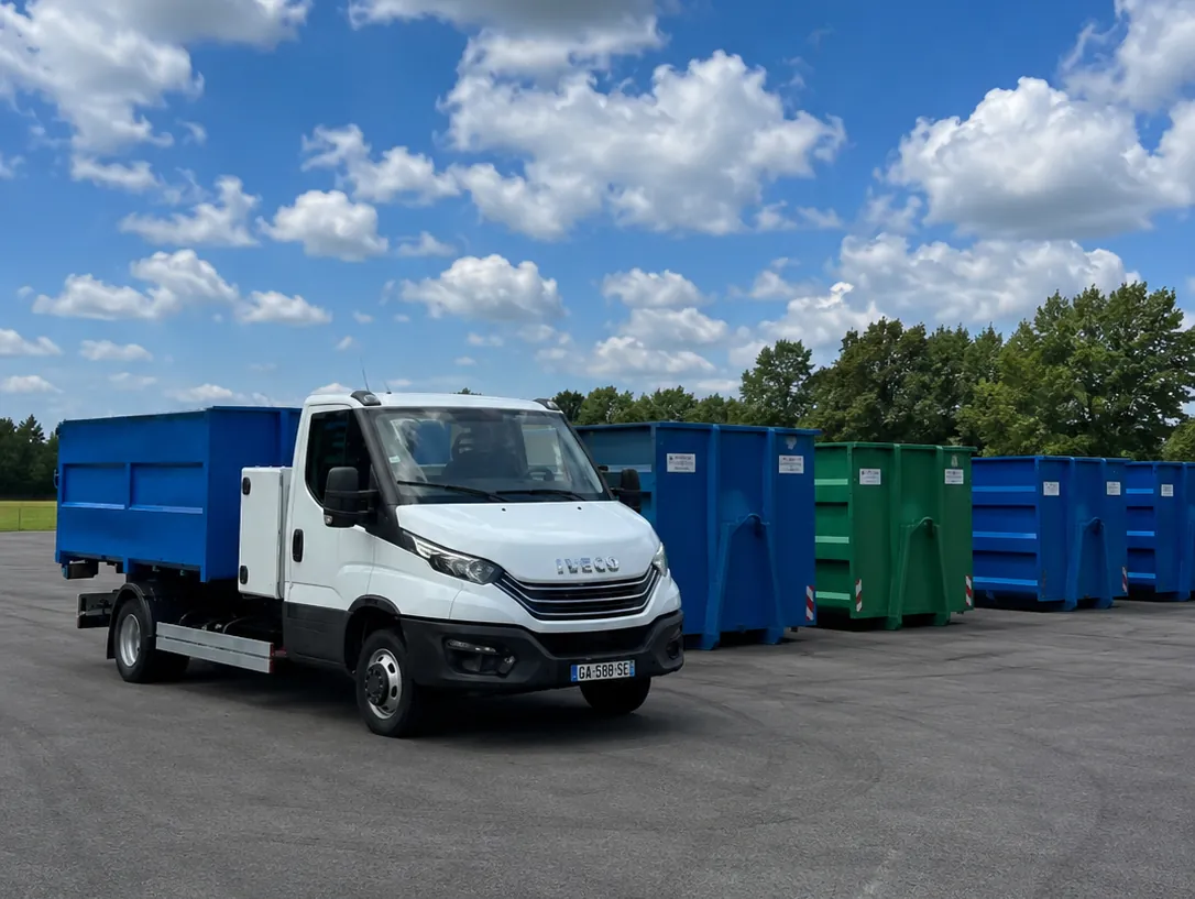 Porte-benne ampliroll LocaBenne — un véhicule léger — chargé d’une benne, devant le parc de bennes de 3 à 12 m³ au dépôt de Drubec, dans le Calvados